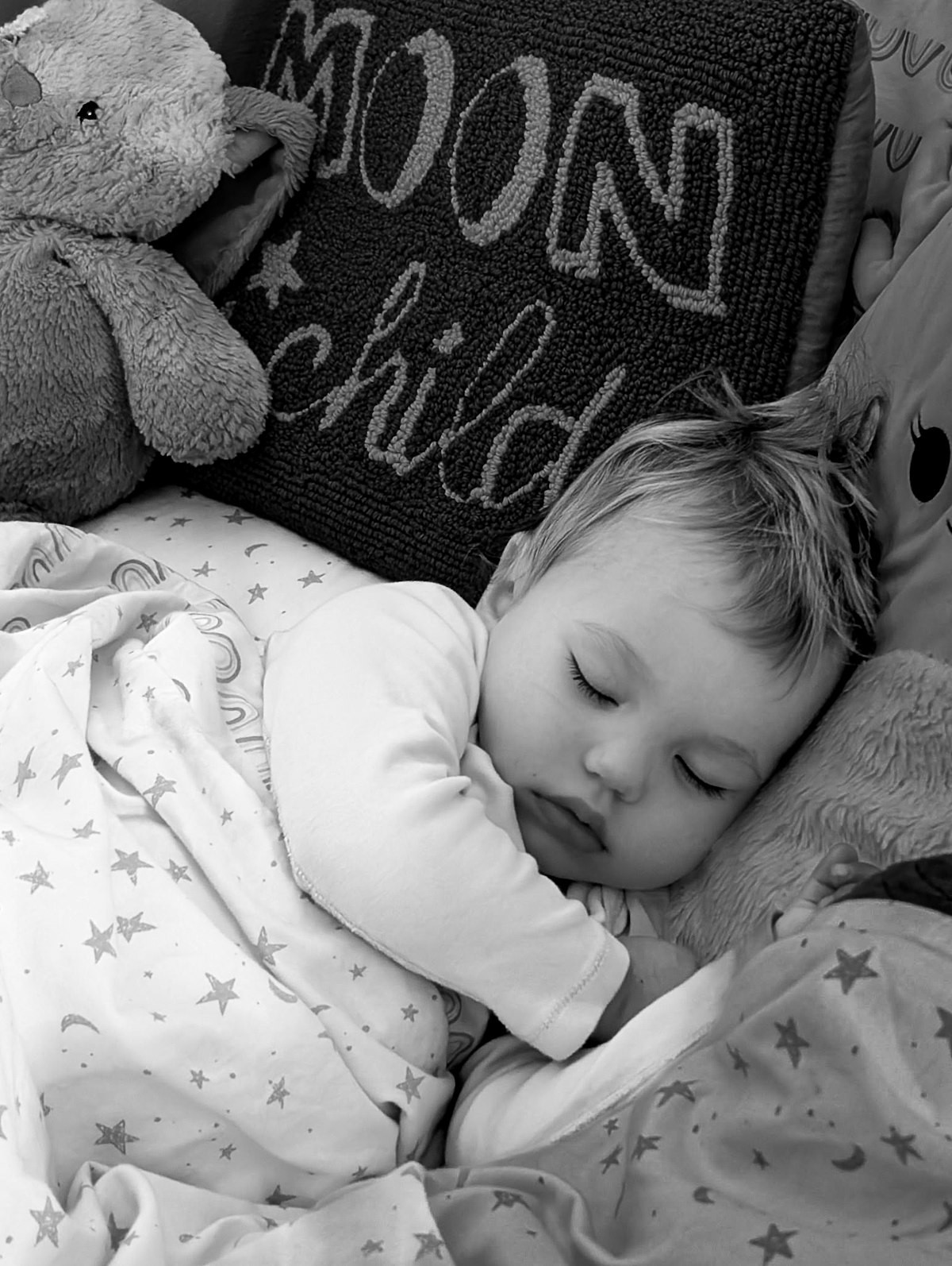 Toddler sleeping soundly surrounded by stuffed animals