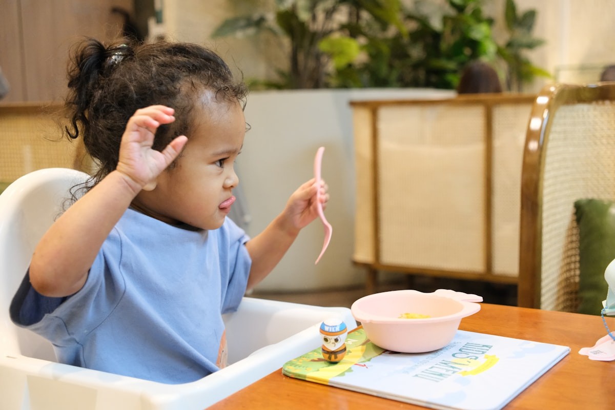 Young child eating from a bowl in a high chair